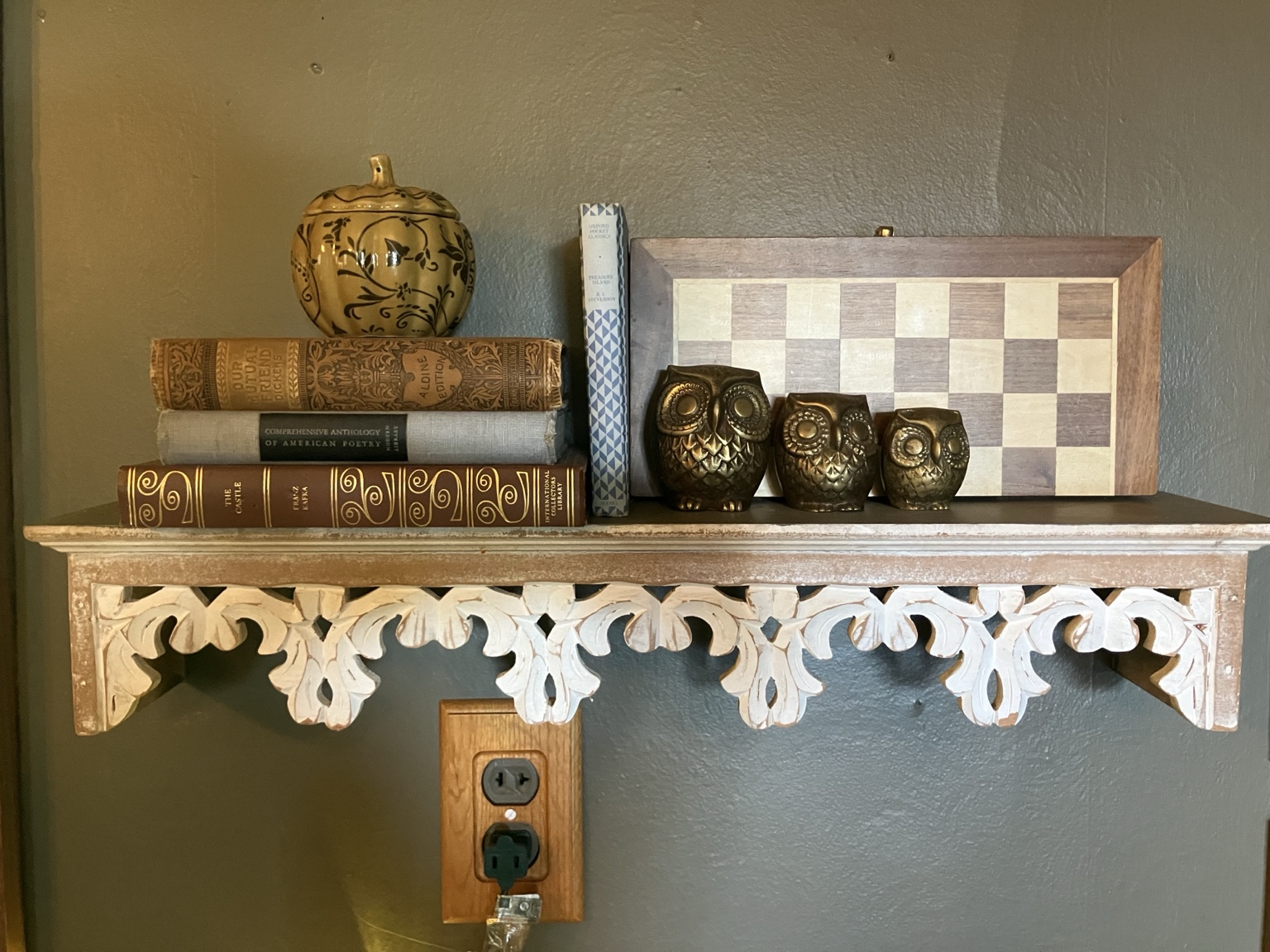 Old books and brass owls on an ornate shelf